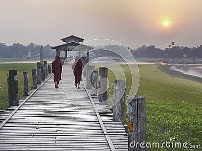 Burmese monks walking across the U Bein Bridge at sunset Editorial Stock Photo